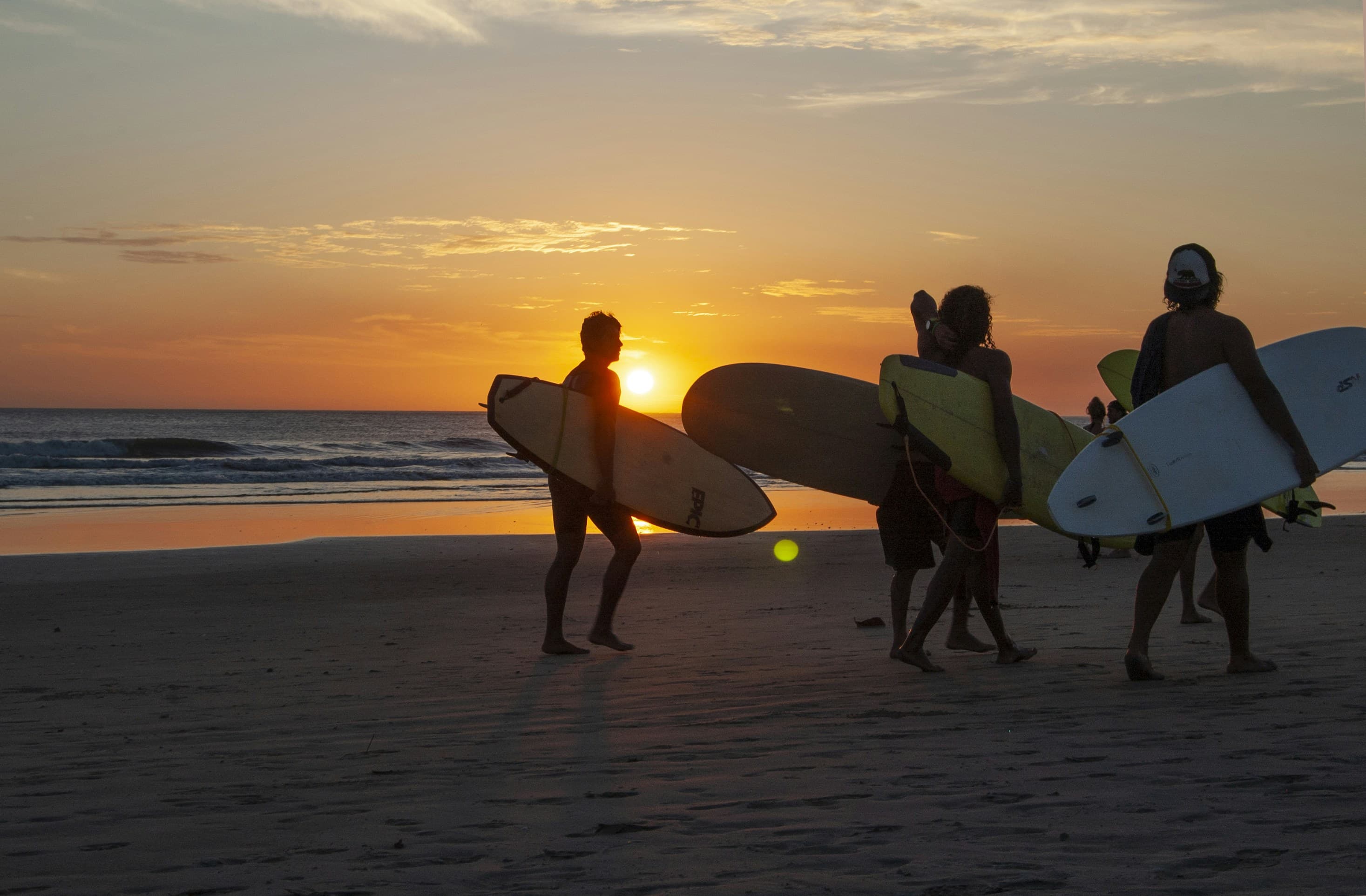 Surfers walking along beach in Playa Grande